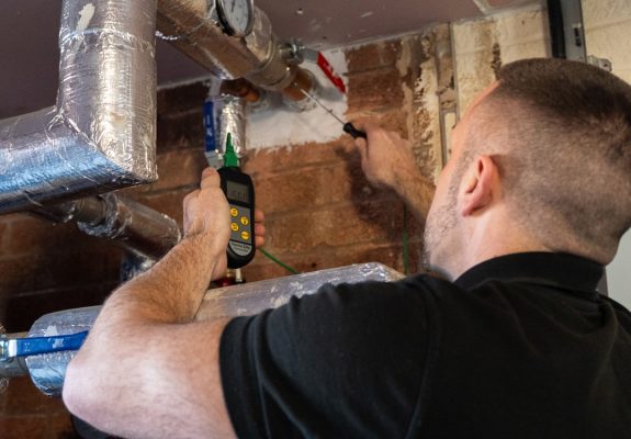 Engineer carrying out water system testing in a commercial plant room